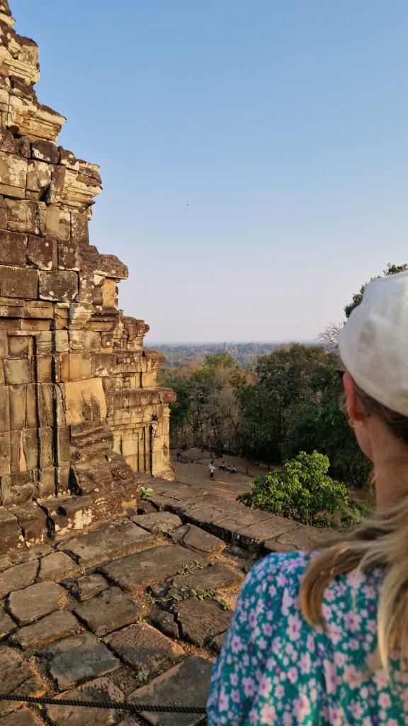 Lena blickt über den grünen Dschungel und steht dabei auf der Terrasse des Steintempels Phnom Bakheng.
