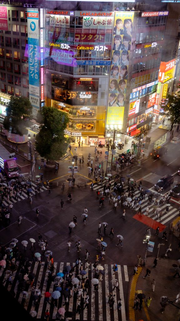 Blick auf viele Menschen, die abends das Shibuya Crossing überqueren. Tokyo & Fuji Podcast-Folge.
