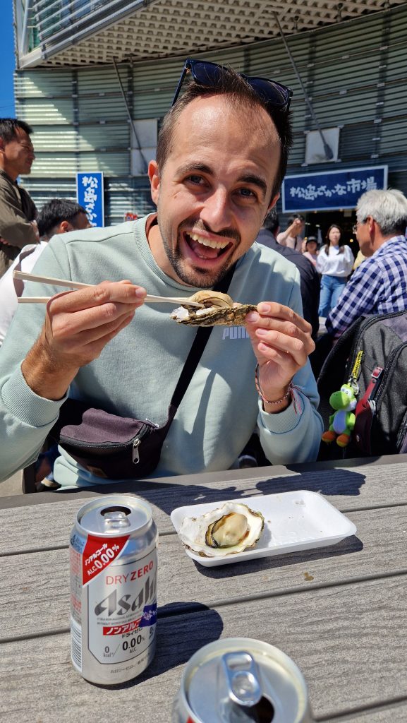 Philippe Isst eine Auster mit Stäbchen auf dem Fischmarkt