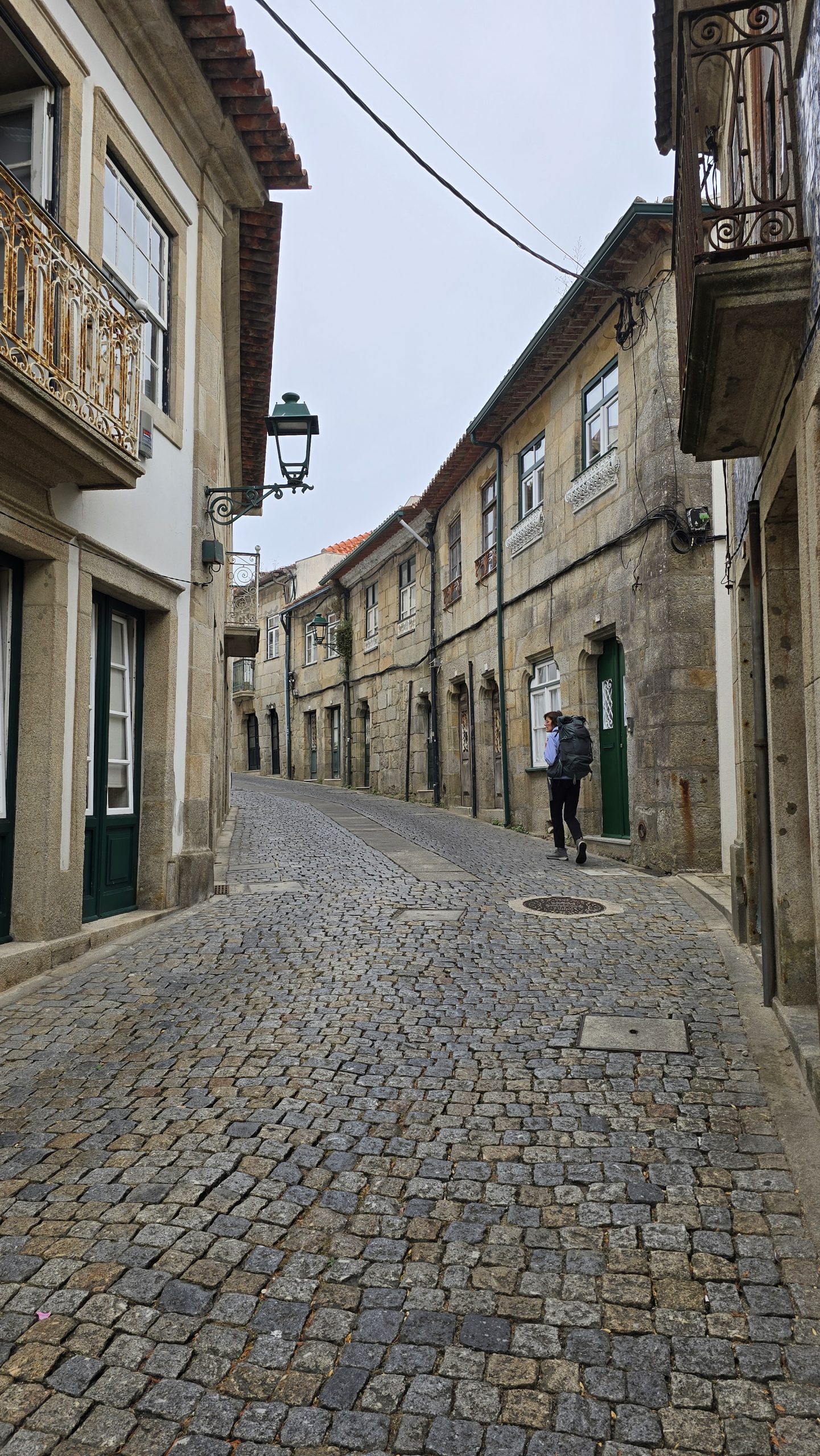 Eine Kofsteinpflasterstraße schlängelt sich durch alte Steingebäude auf dem Jakbosweg