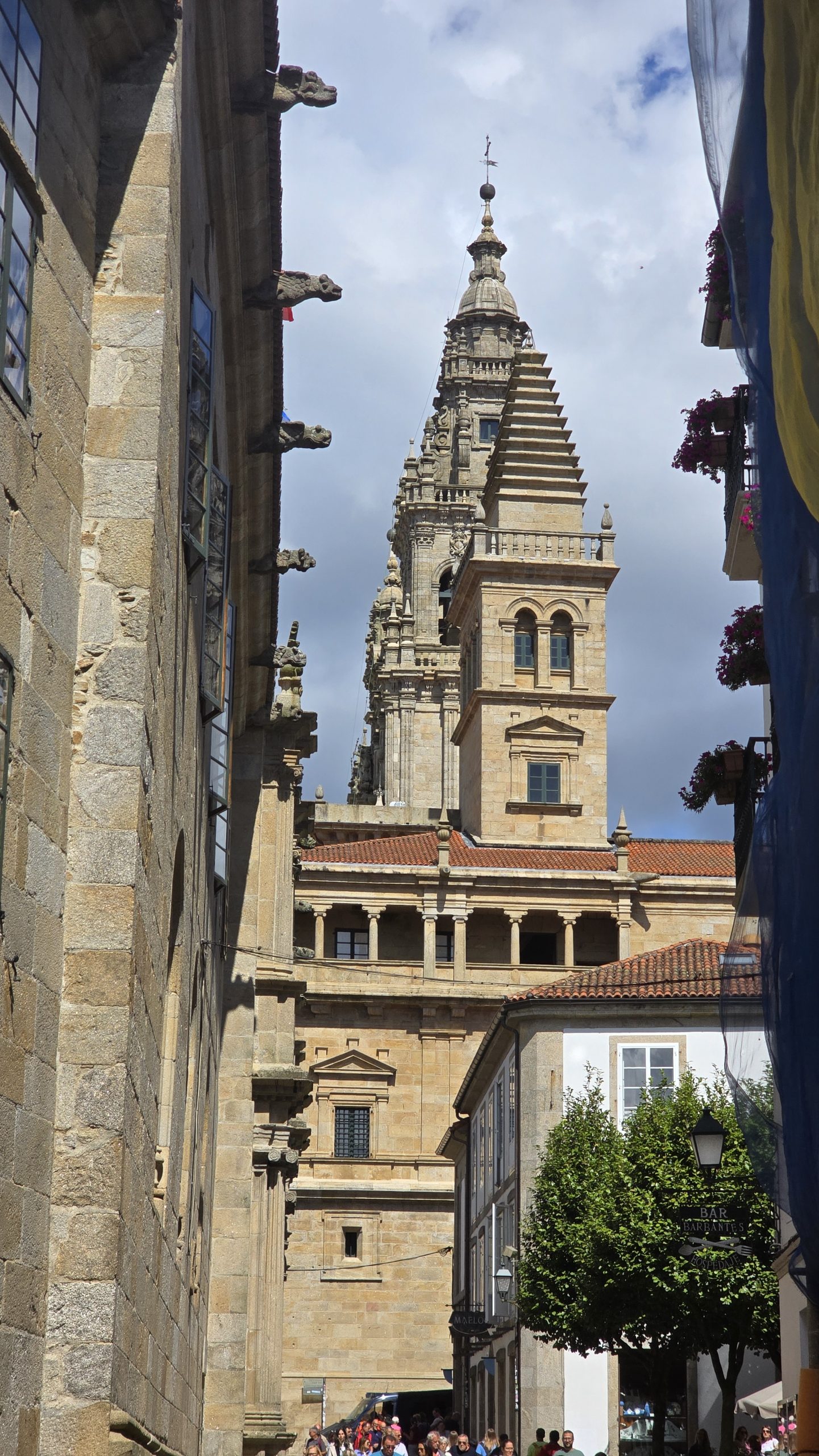 Blick durch die schmalen Gassen mit Steinhäusern auf den Spitzen Turm der Kathedrale von Santiago