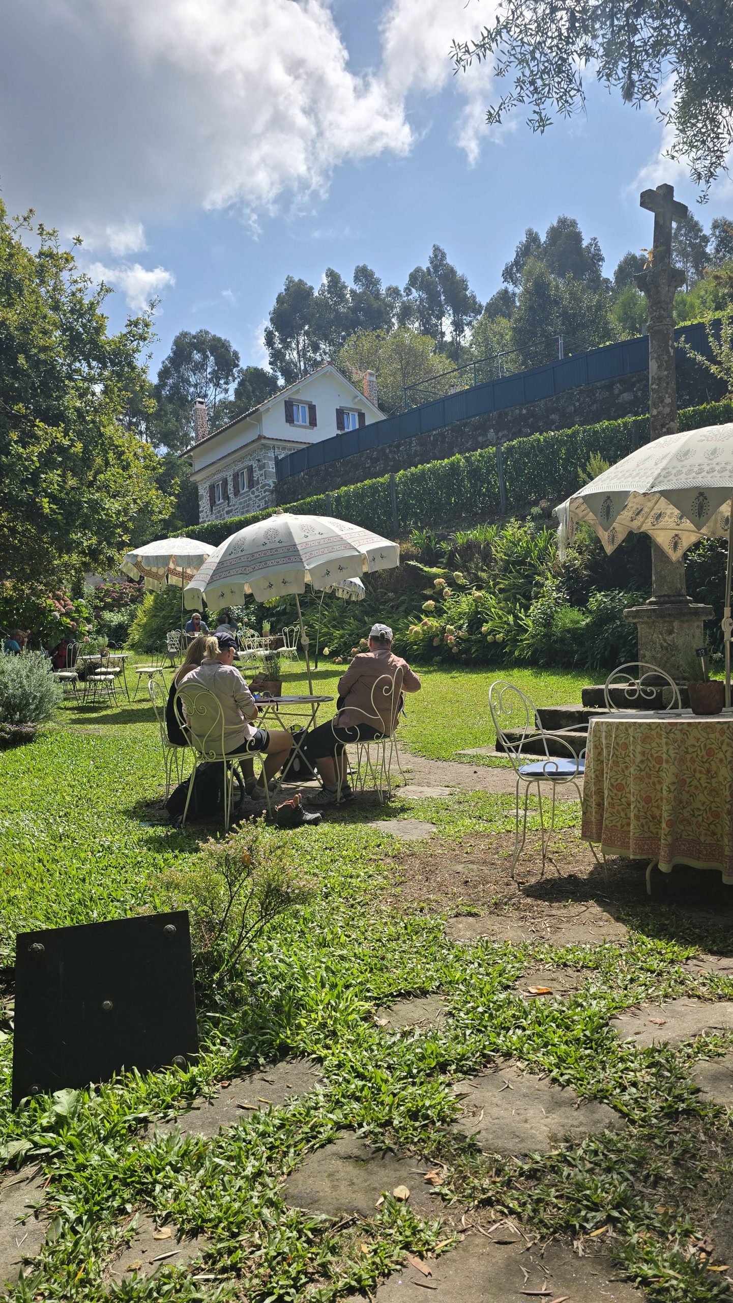 Sonnenschirme und Tische stehen in einem Karten mit grünem Gras und Bäumen