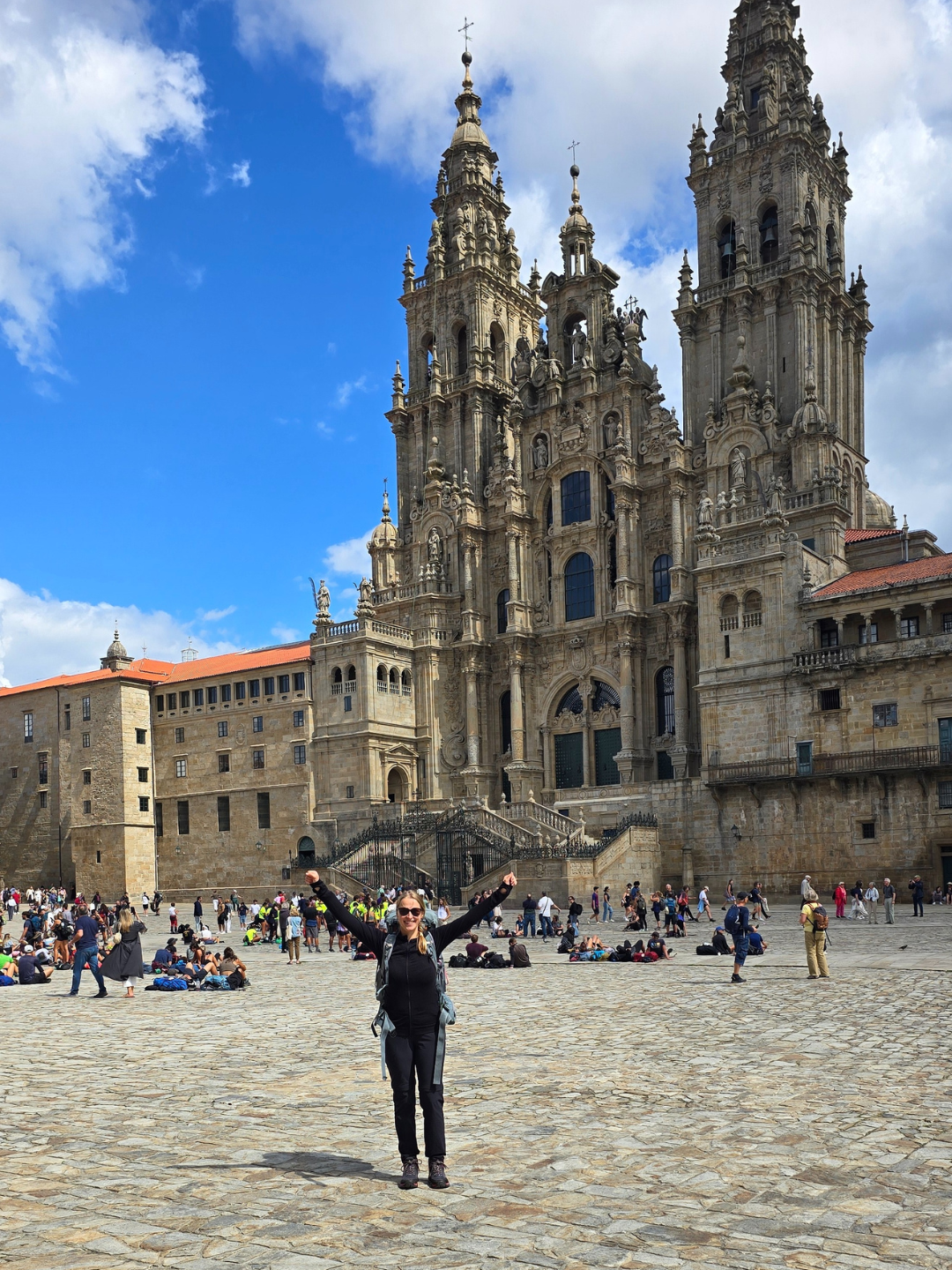 Lena steht auf dem Platz vor der Kathedrale von Santiago und streckt die Arme in die Luft