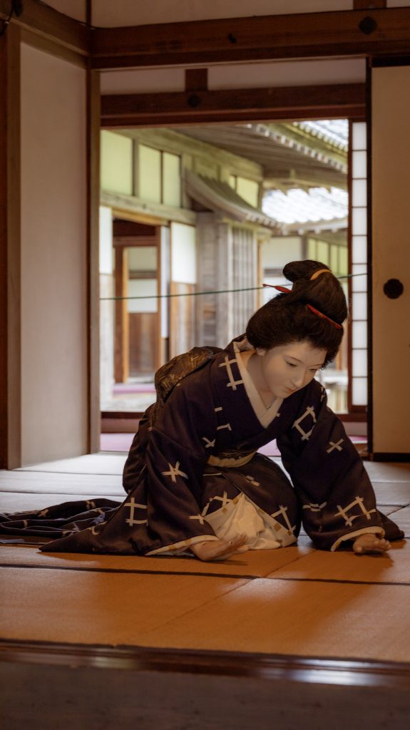 Eine Puppe mit traditioneller Samurai Kleidung kniet auf dem Boden