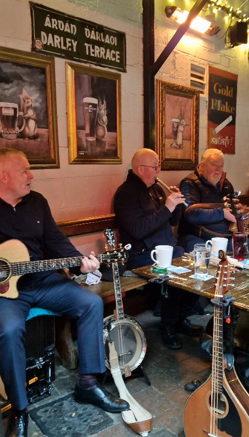 Drei Männer in dunkelblauen Pullis spielen irische Musik