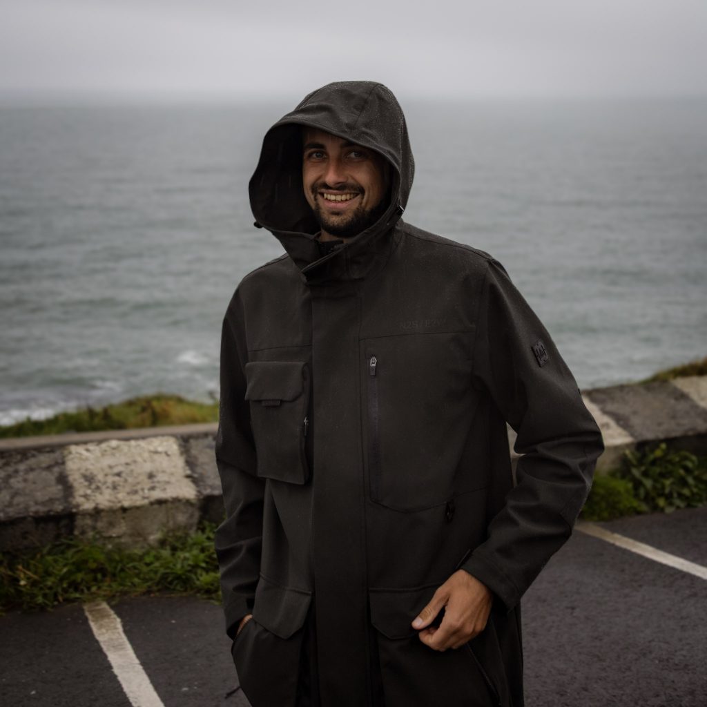 Philippe steht mit einer Regenjacke an der Küste