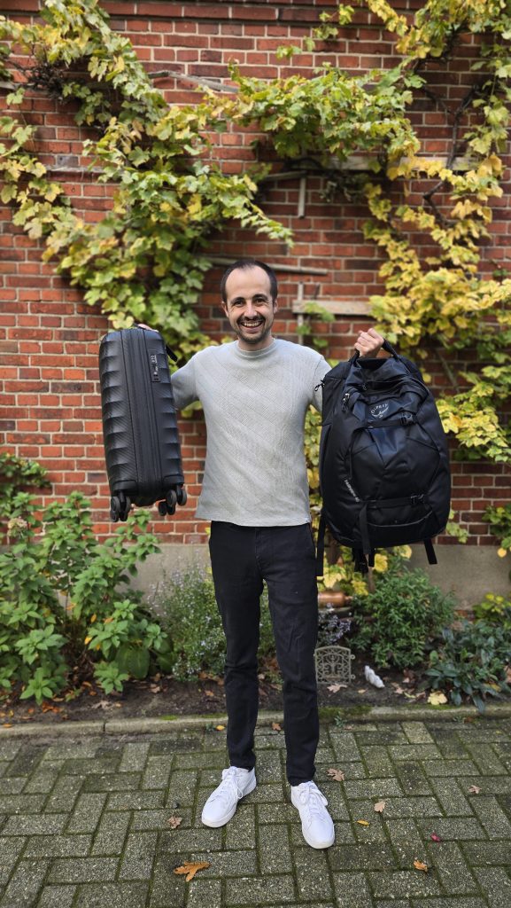 Philippe wie er einen kleinen Koffer und ein Rucksack hoch hält