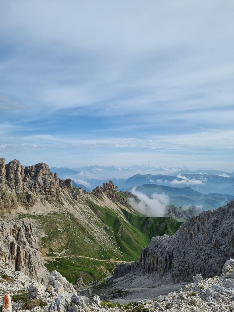 Ausblick vom Molignonpass: Schroffe Felszacken des Rosengartenmassivs, den 3000m hohen Kesselkogel und sattgrüne Bergwiesen 