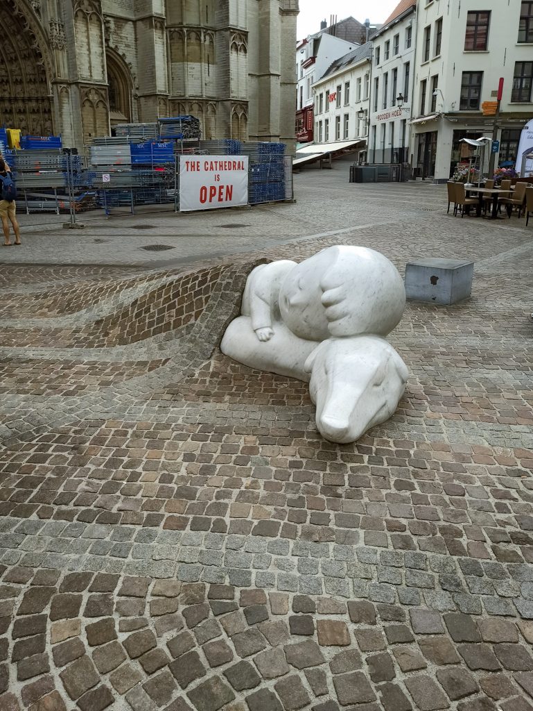 Die weißen Figuren Nello und Patrasche eingebettet im Kopfsteinpflaster mit der Liebfrauenkathedrale im Hintergrund