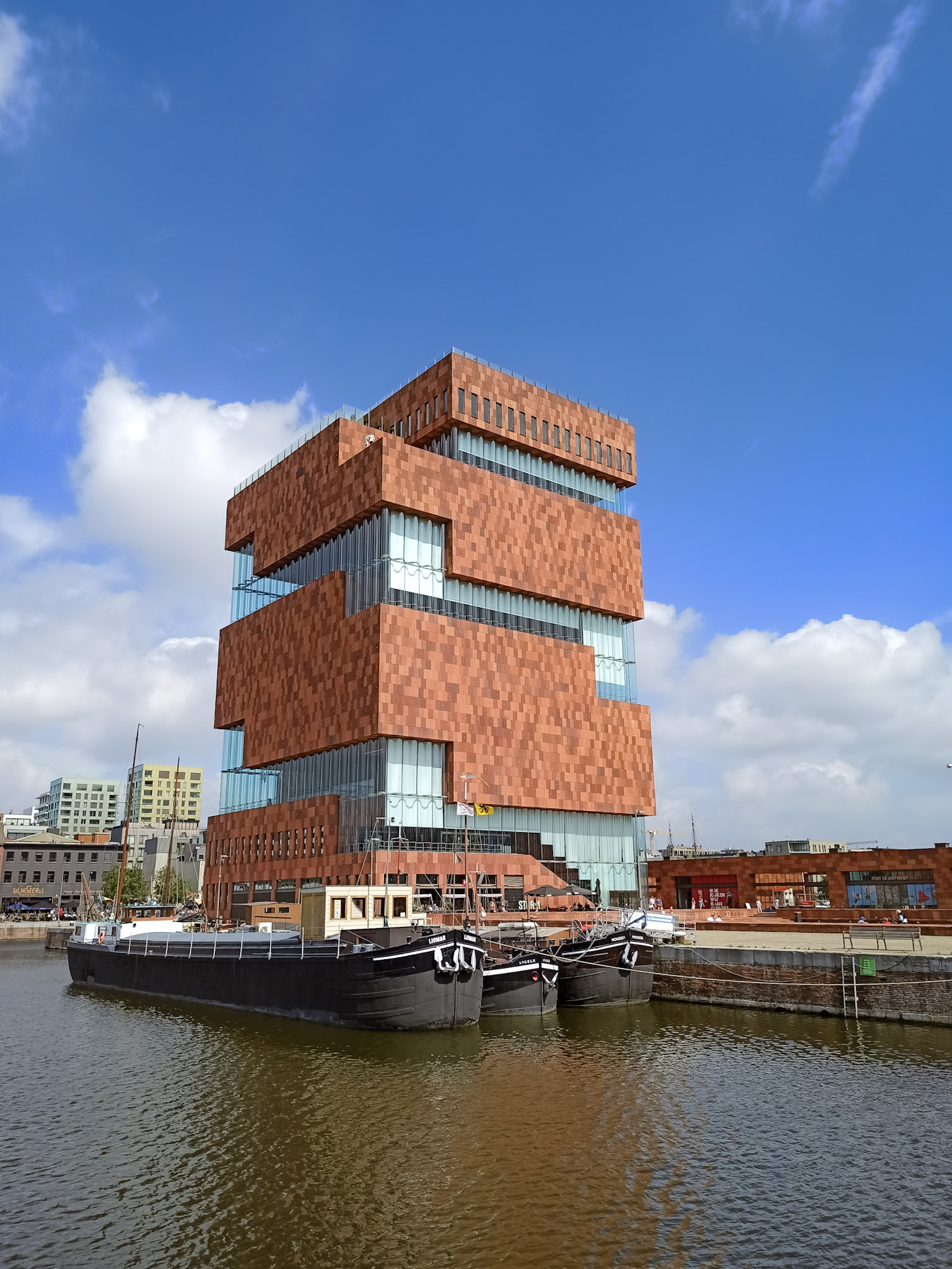 das MAS Museum bestehend aus Backstein und Glas. Davor befindet sich das Hafenbecken mit zwei größeren Schiffen.