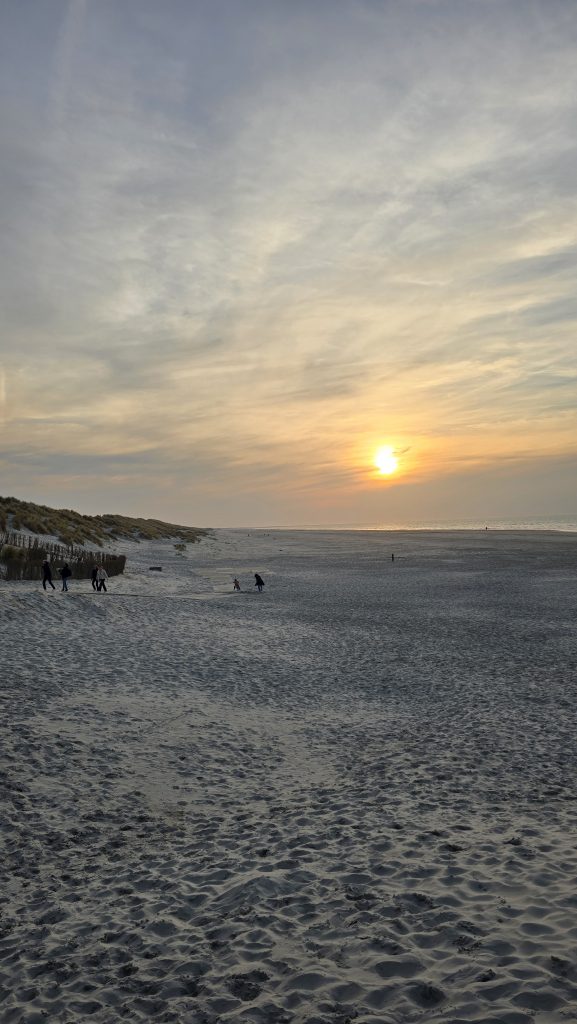 feiner Sandstrand bei Sonnenuntergang mit wolkigem Himmel