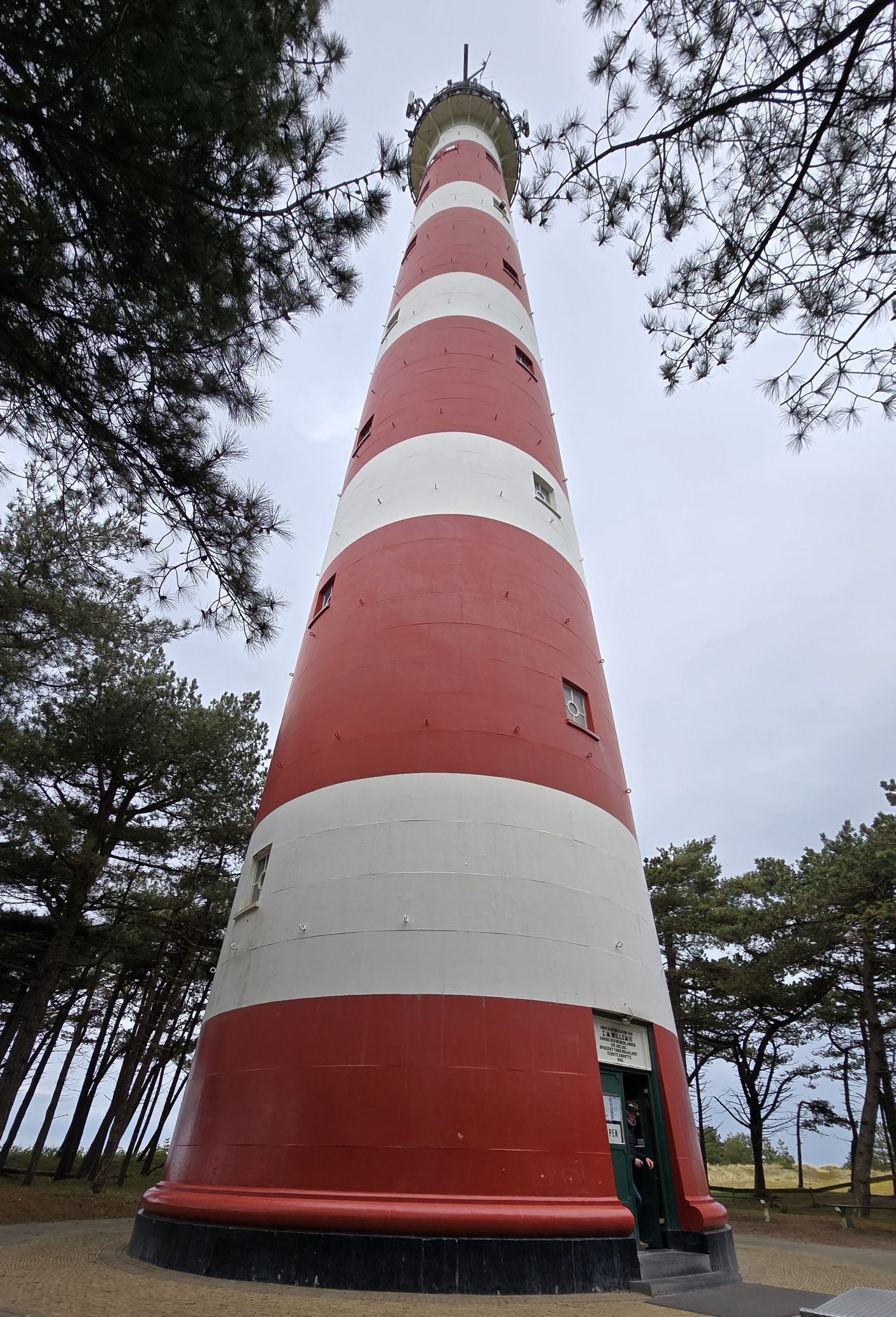 rot-weiß gestreifter 55meter hoher Leuchtturm in mitten von Nadelbäumen