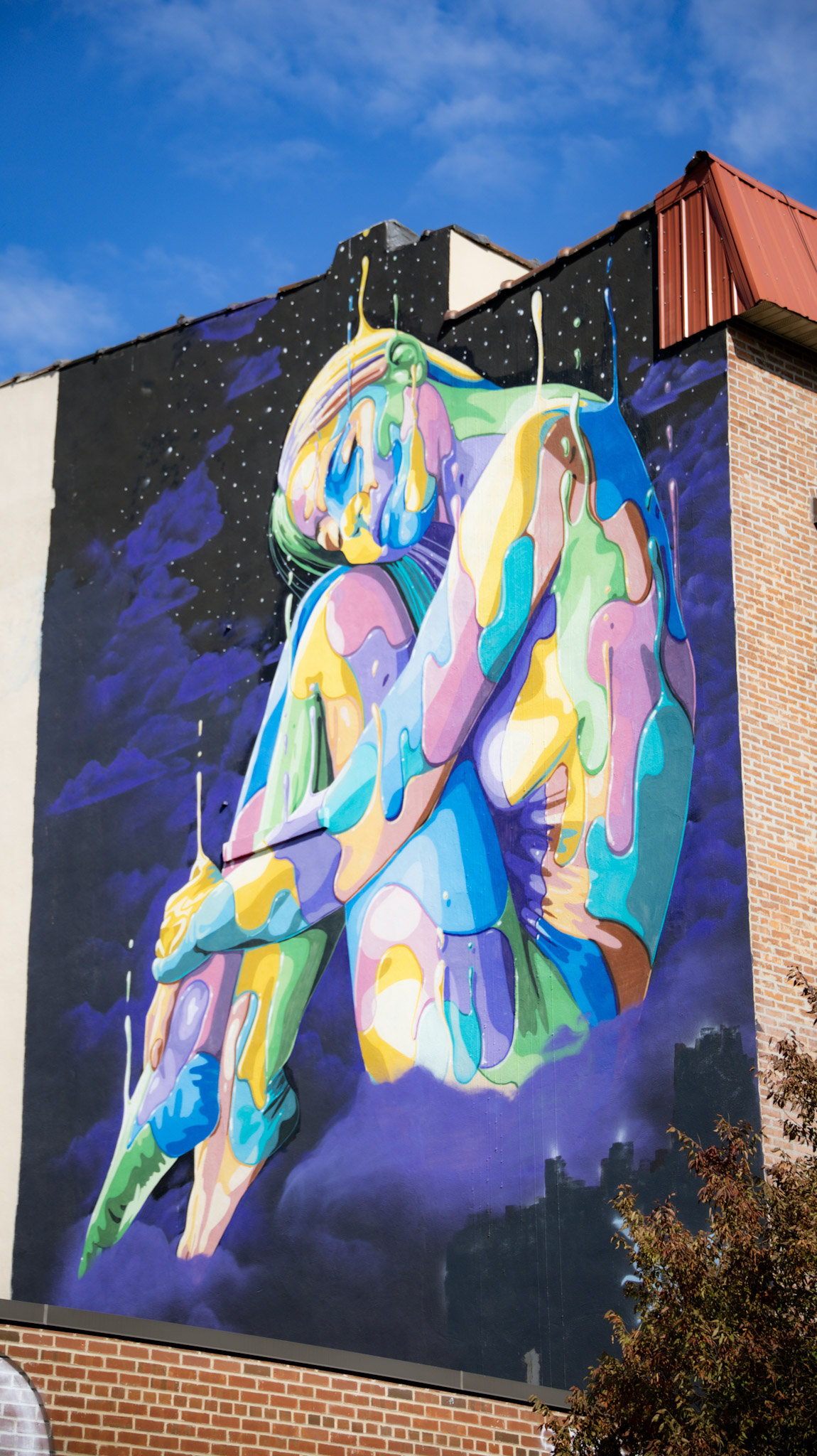 Streetart: Frau Körper in Embryo Stellung, gemalt aus vielen bunten Puzzle-artigen Farbklecksen